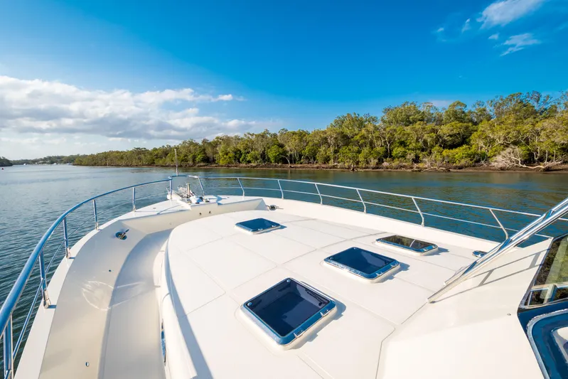  Yacht Photos Pics 2026 Alaska 59 Sedan yacht cruising on a serene river with lush green shoreline.