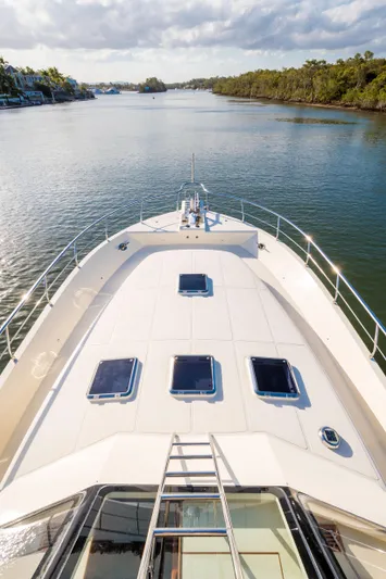  Yacht Photos Pics 2026 Alaska 59 Sedan yacht cruising on a serene river with lush greenery.