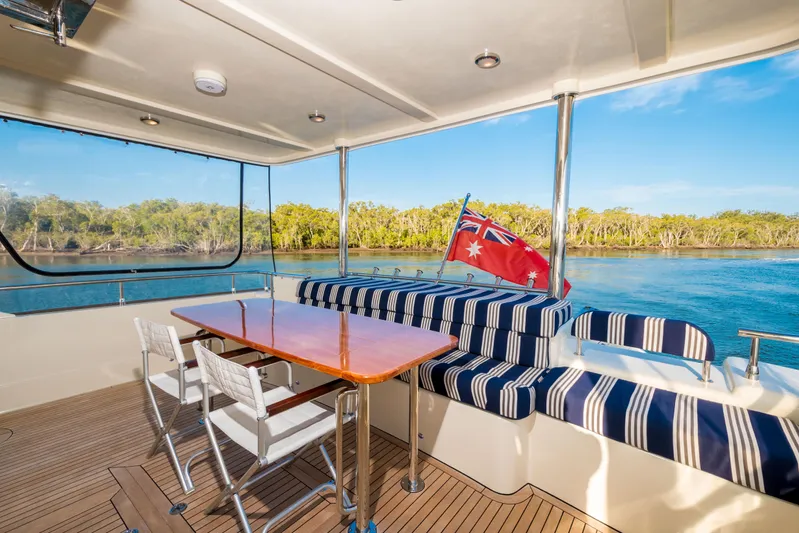  Yacht Photos Pics Luxurious Alaska 59 Sedan yacht interior with striped seating, table, and scenic water view.