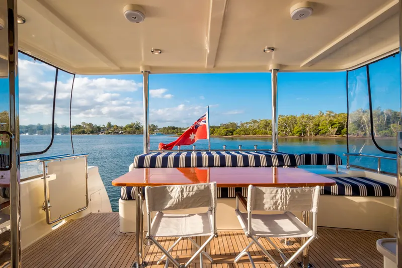  Yacht Photos Pics Luxurious 2026 Alaska 59 Sedan yacht deck with seating, table, and scenic water view.