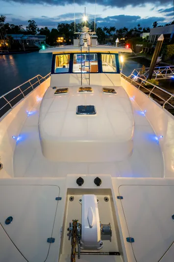  Yacht Photos Pics 2026 Alaska 59 Sedan yacht, illuminated deck at dusk, docked by waterfront homes.