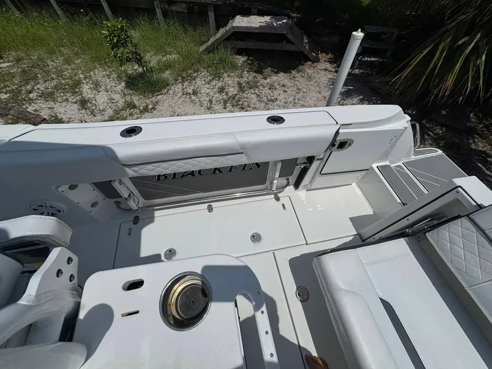  Yacht Photos Pics 2021 Blackfin 252 CC boat interior with white seating and deck, near grassy area.