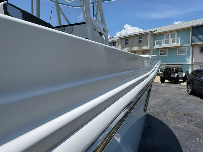  Yacht Photos Pics 2021 Blackfin 252 CC boat side view, parked near residential buildings under a clear sky.