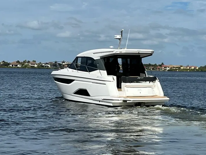 Inventory Clearance Yacht Photos Pics 2023 Bavaria R40 Coupe cruising on a serene lake under a partly cloudy sky.