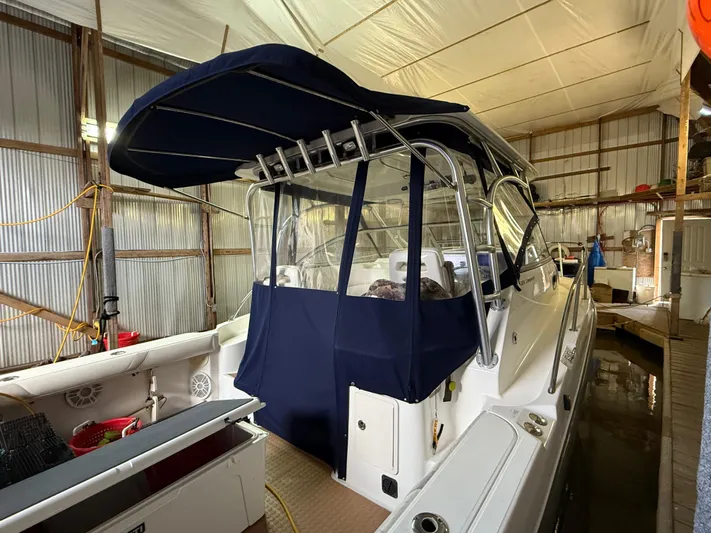  Yacht Photos Pics 2006 Boston Whaler 305 Conquest boat in storage with blue canopy and enclosed cockpit.