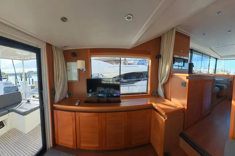Balena Yacht Photos Pics Interior of 2015 Beneteau Swift Trawler 50 with TV, wood cabinetry, and marina view.