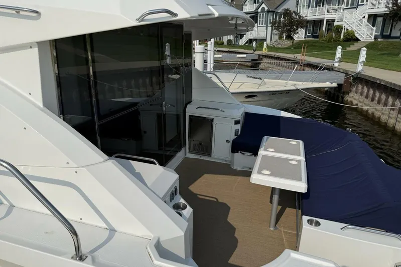  Yacht Photos Pics 2013 Cruisers Yachts Cantius with outdoor seating and table, docked near waterfront homes.