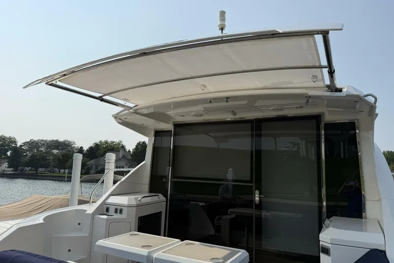  Yacht Photos Pics 2013 Cruisers Yachts Cantius with retractable sunshade, docked by a serene waterfront.