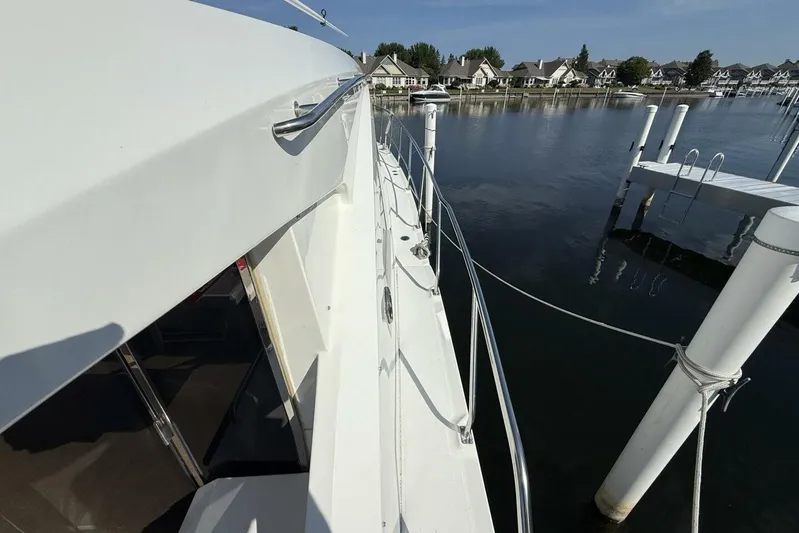  Yacht Photos Pics 2013 Cruisers Yachts Cantius docked by waterfront homes, showcasing sleek design and railing.