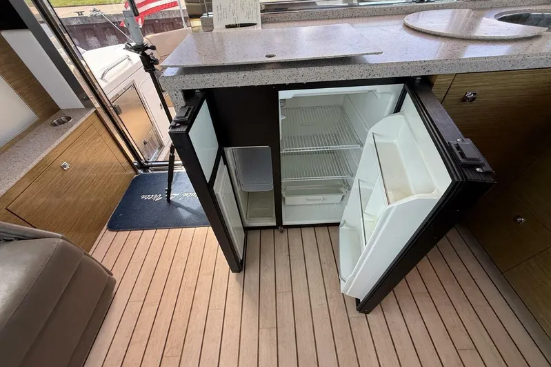  Yacht Photos Pics 2013 Cruisers Yachts Cantius interior with open mini fridge and wooden flooring.