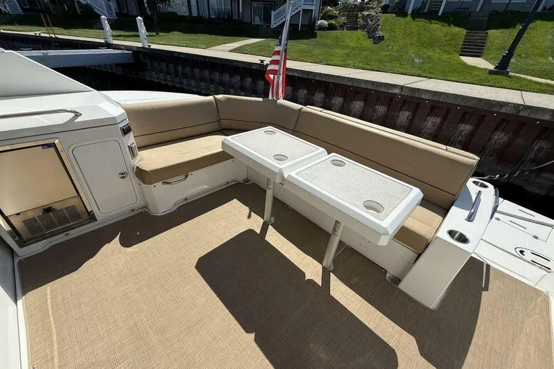  Yacht Photos Pics 2013 Cruisers Yachts Cantius deck with beige seating and dual tables, docked by green lawn.