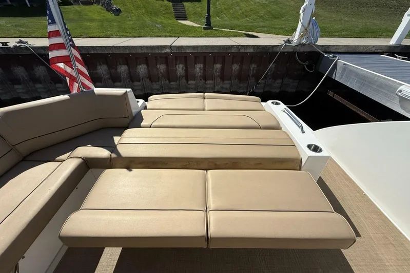  Yacht Photos Pics 2013 Cruisers Yachts Cantius with beige seating and American flag, docked by grassy area.
