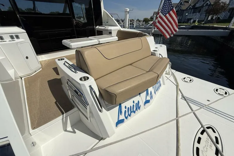  Yacht Photos Pics 2013 Cruisers Yachts Cantius with beige seating and American flag, docked by waterfront homes.