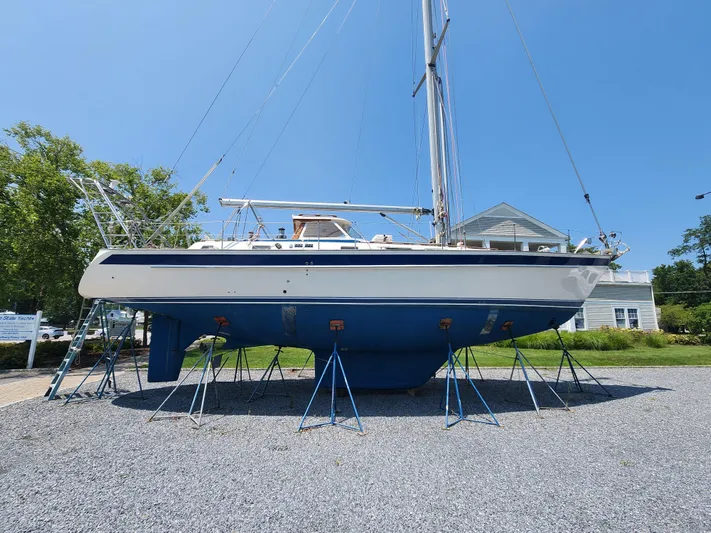 Sonder Yacht Photos Pics 2003 Hallberg-Rassy 46 sailboat on stands, blue hull, sunny day, gravel ground.