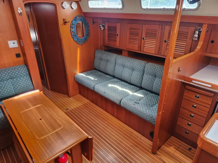 Sonder Yacht Photos Pics Interior of 2003 Hallberg-Rassy 46 yacht with wooden furnishings and blue cushioned seating.
