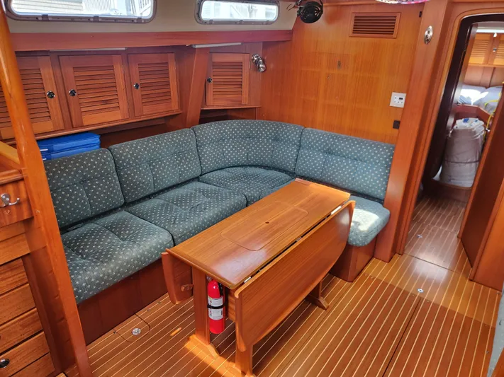Sonder Yacht Photos Pics Interior of 2003 Hallberg-Rassy 46 yacht with wooden furnishings and blue cushioned seating.