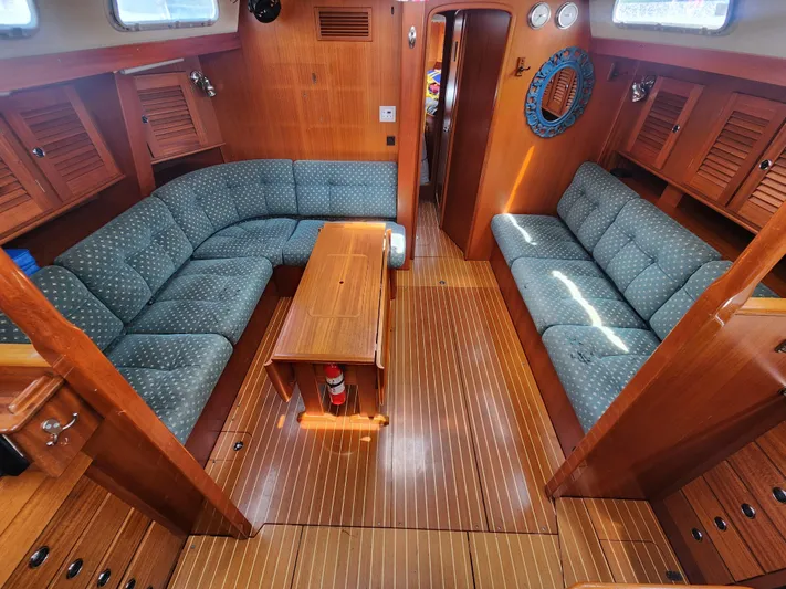 Sonder Yacht Photos Pics Interior of 2003 Hallberg-Rassy 46 yacht with wooden finish and blue upholstered seating.