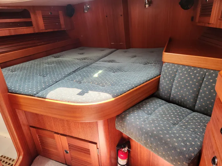 Sonder Yacht Photos Pics Cozy cabin interior of 2003 Hallberg-Rassy 46 yacht with wooden finish and blue upholstery.