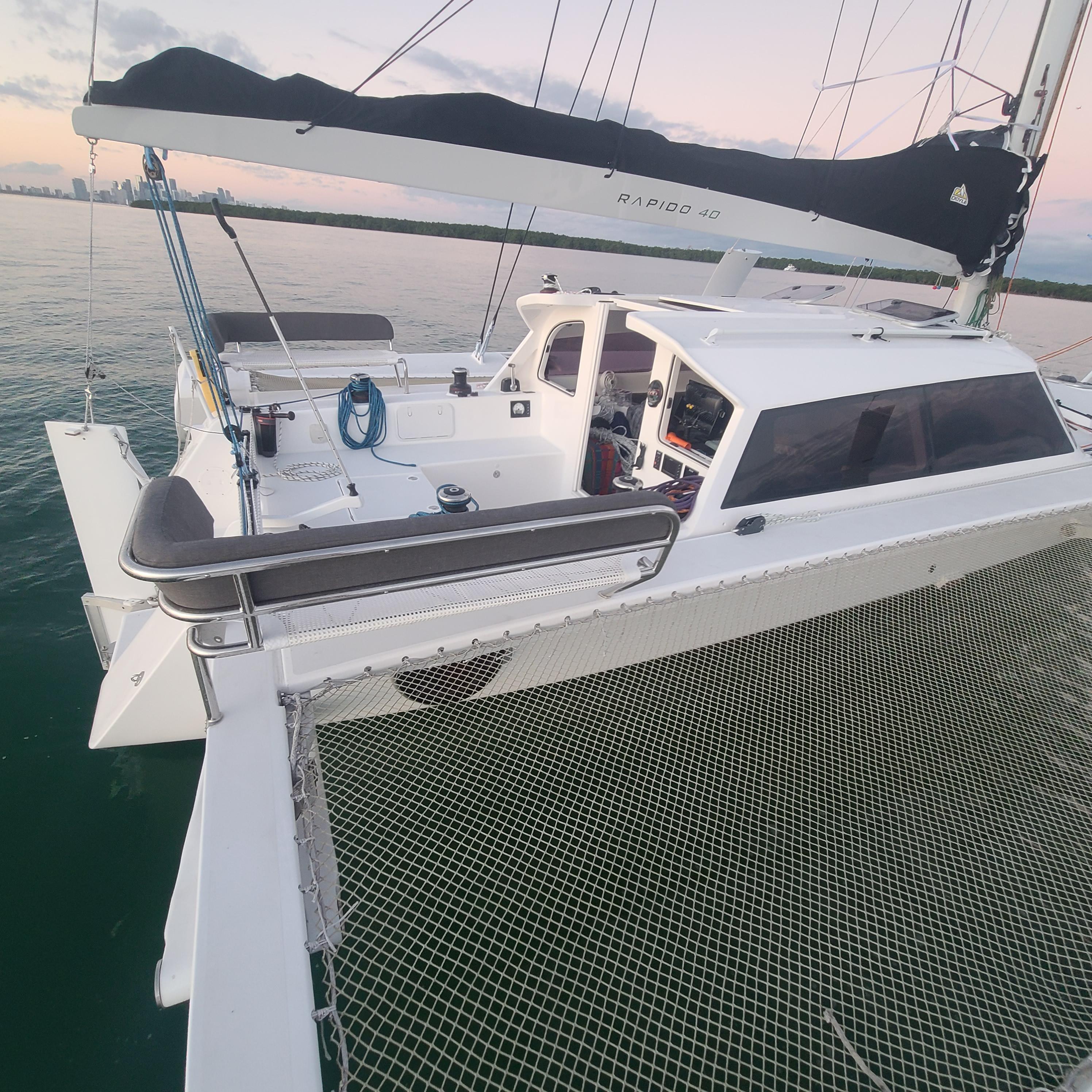 2025 Rapido 40 catamaran on calm water at sunset, showcasing deck and sail.