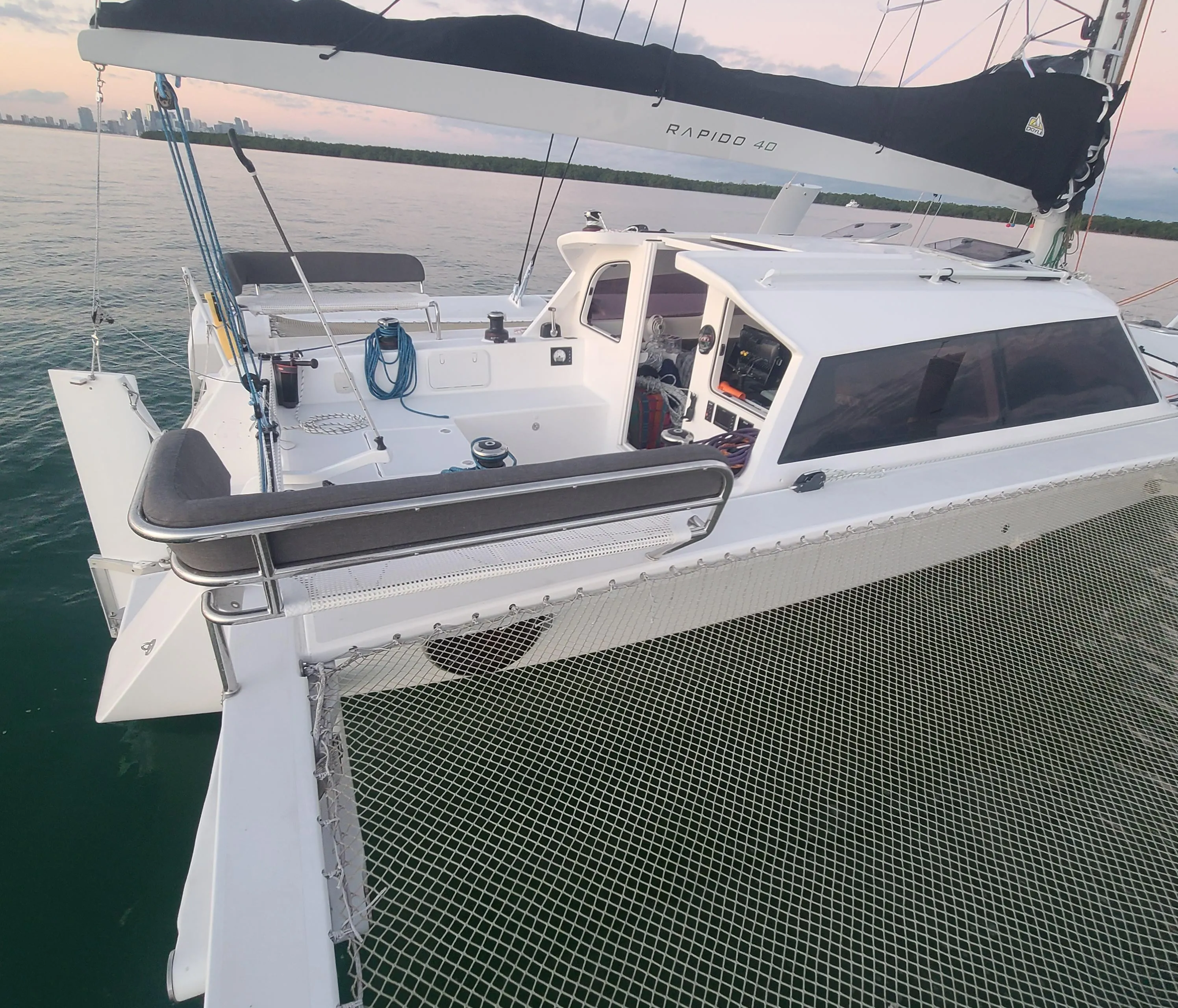 2025 Rapido 40 catamaran on calm water at sunset, showcasing deck and sail.