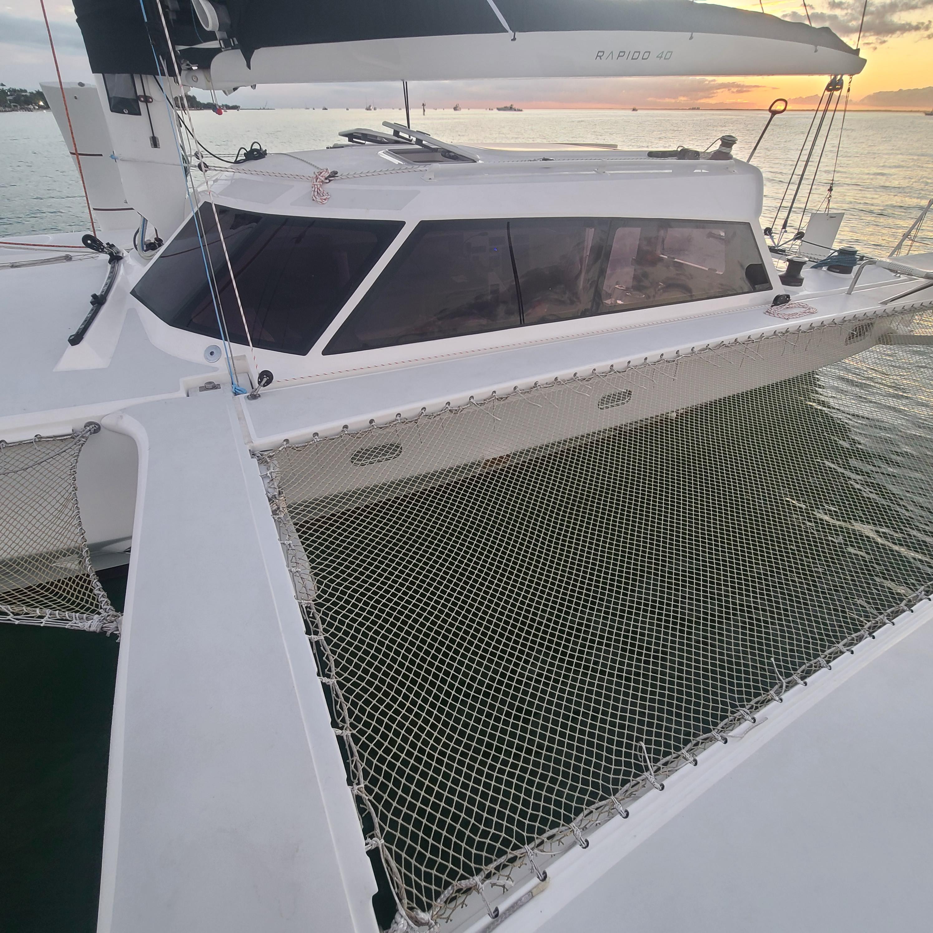 2025 Rapido 40 catamaran with netting, docked at sunset.