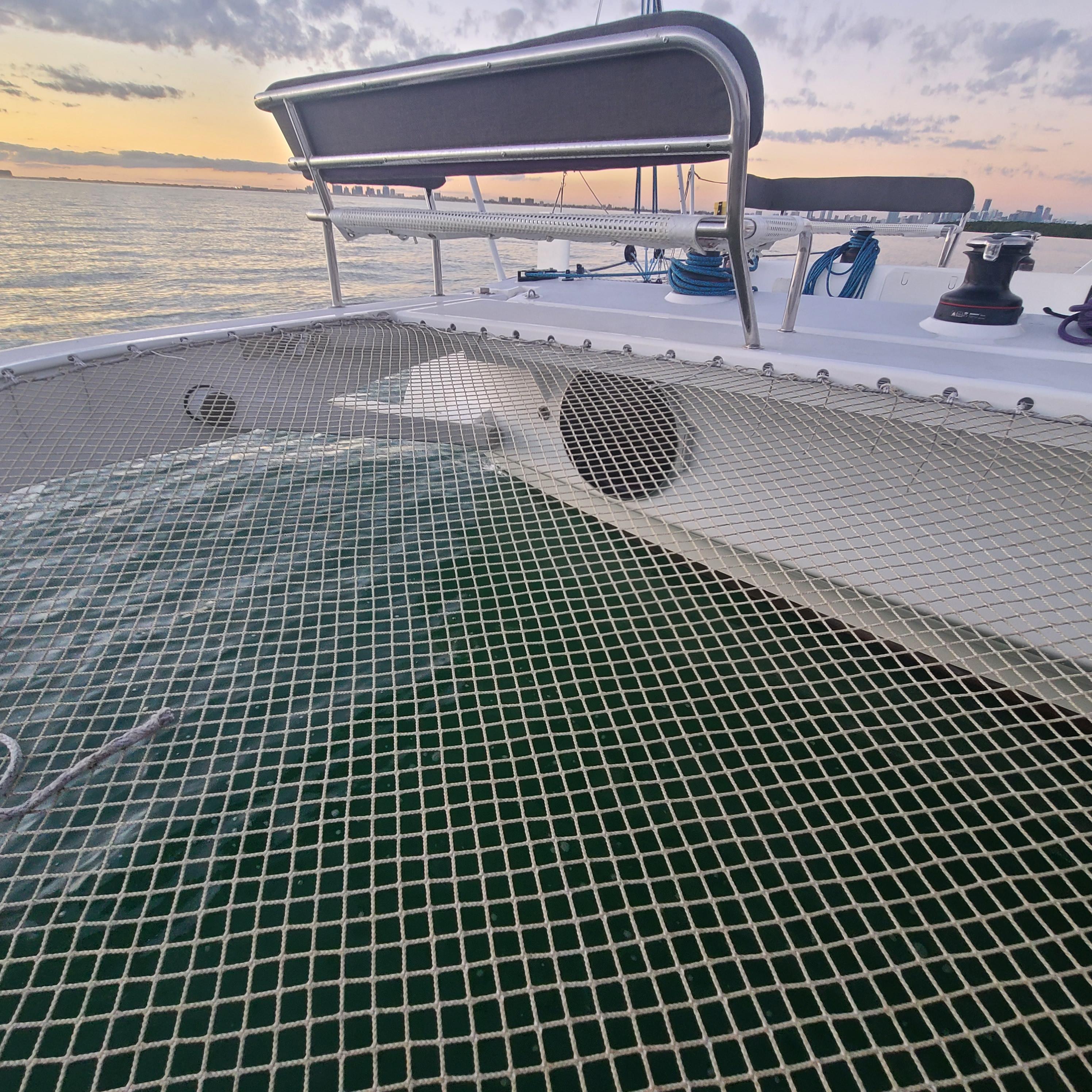 2025 Rapido 40 catamaran deck with netting, ocean view at sunset.