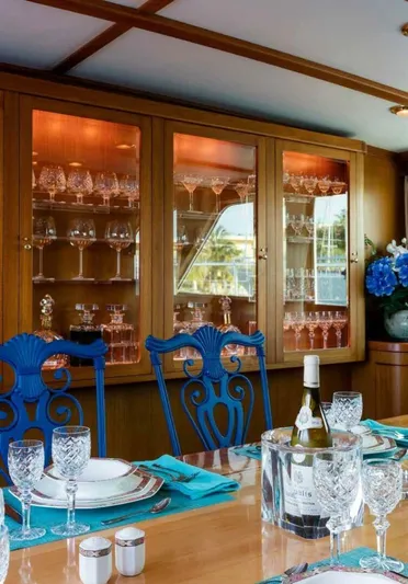 Seafari Yacht Photos Pics Elegant dining area on 1975 Burger Raised Pilothouse CPMY yacht with glassware and blue chairs.