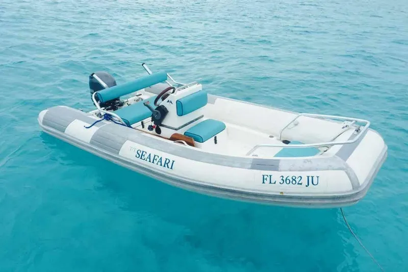 Seafari Yacht Photos Pics Small inflatable boat named "SEAFARI" floating on clear blue water.