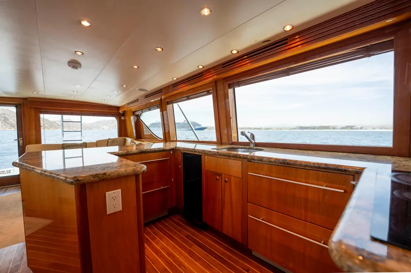 Strictly Business Yacht Photos Pics Luxurious interior of 2004 Hatteras 65 Enclosed Bridge yacht with wooden cabinetry and ocean view.