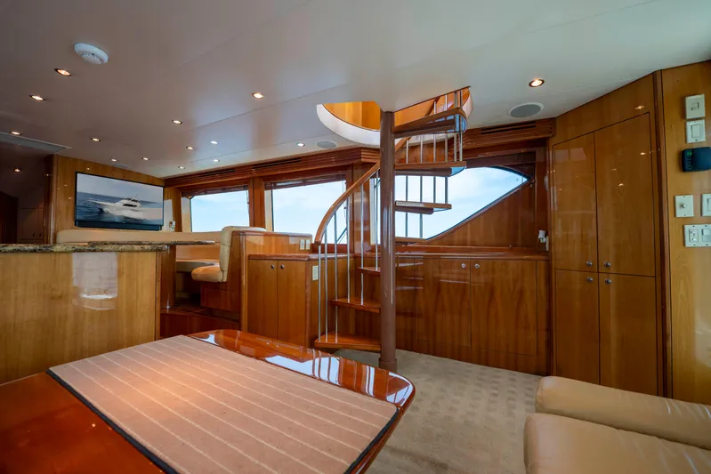 Strictly Business Yacht Photos Pics Luxurious interior of 2004 Hatteras 65 Enclosed Bridge yacht with spiral staircase and wood finishes.