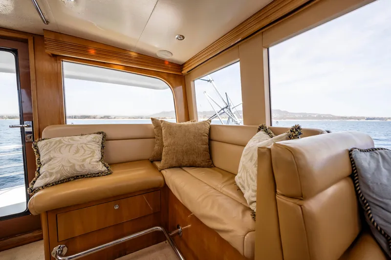 Strictly Business Yacht Photos Pics Luxurious interior of 2004 Hatteras 65 Enclosed Bridge yacht with plush seating and scenic views.