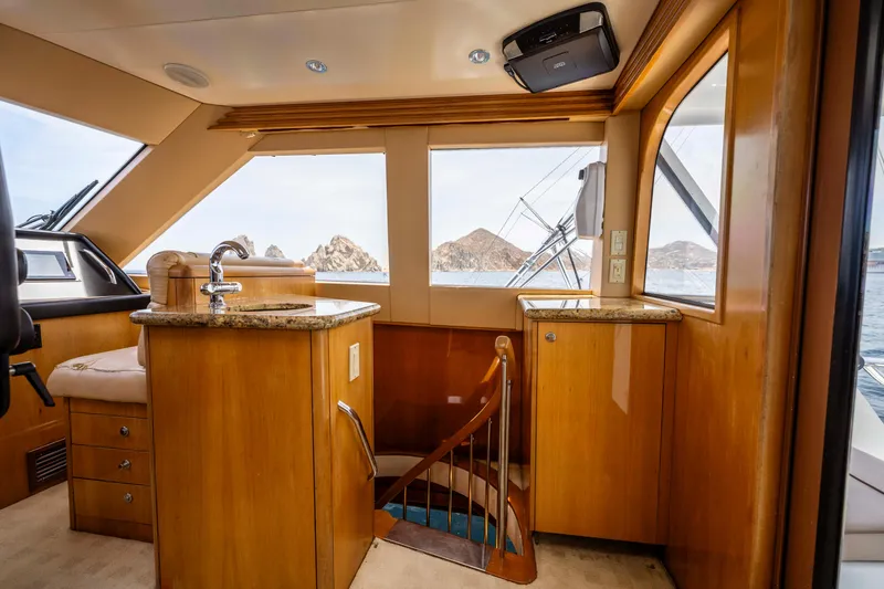 Strictly Business Yacht Photos Pics Luxurious interior of 2004 Hatteras 65 Enclosed Bridge yacht with wooden finishes and ocean view.