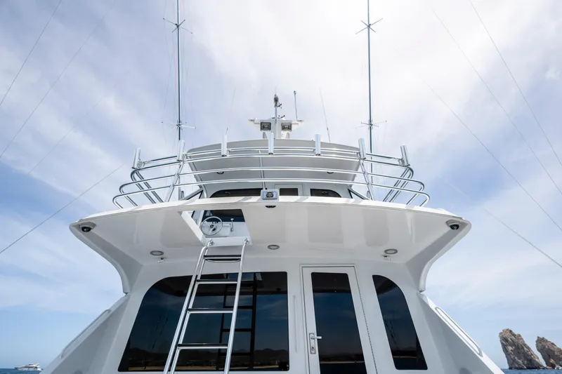 Strictly Business Yacht Photos Pics 2004 Hatteras 65 Enclosed Bridge yacht with sleek design and multiple antennas against a blue sky.