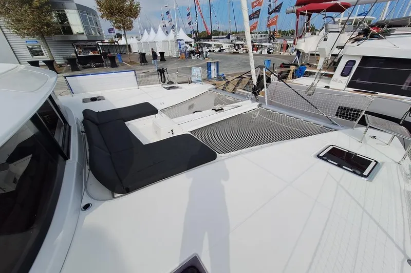 Yoff Yacht Photos Pics 2023 Lagoon 46 catamaran deck with seating and netting at a boat show.