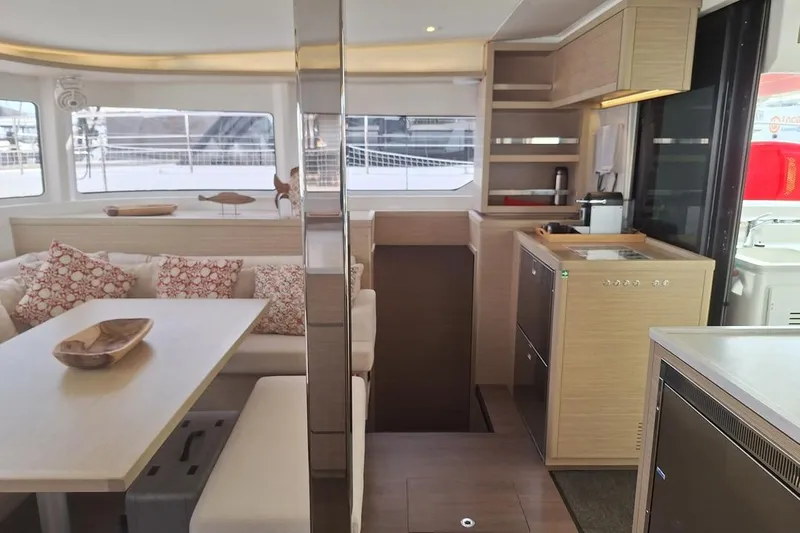 Yoff Yacht Photos Pics Modern interior of a 2023 Lagoon 46 catamaran with kitchen and seating area.