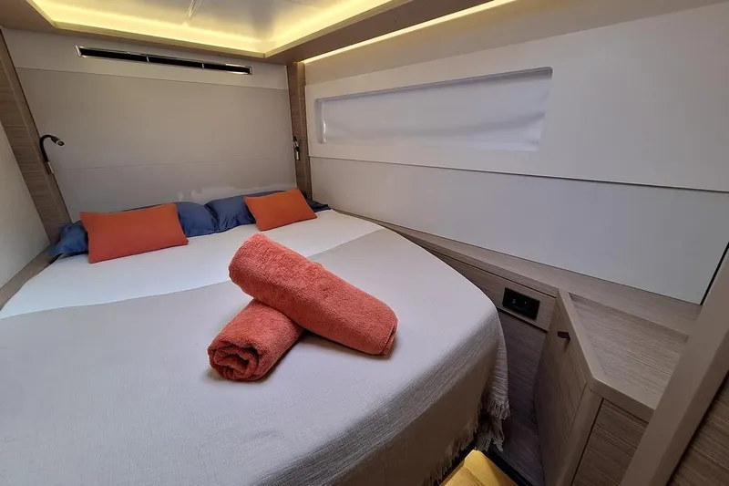 Yoff Yacht Photos Pics Luxurious cabin interior of 2023 Lagoon 46 yacht with cozy bedding and ambient lighting.