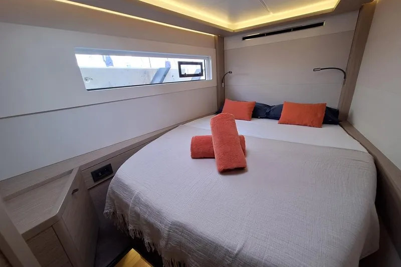 Yoff Yacht Photos Pics Luxurious cabin interior of 2023 Lagoon 46 yacht with cozy bedding and modern lighting.