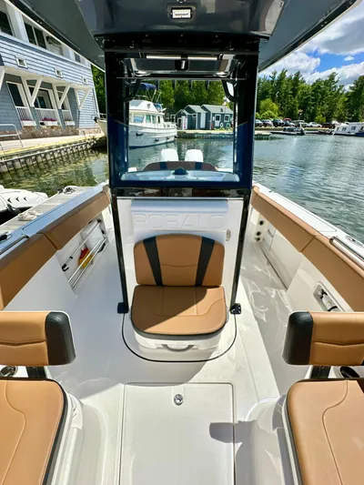  Yacht Photos Pics 2024 Robalo R250 Center Console boat interior with tan seating, docked by waterfront homes.