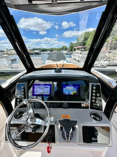  Yacht Photos Pics 2024 Robalo R250 Center Console dashboard with dual navigation screens, steering wheel, and marina view.