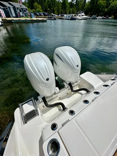  Yacht Photos Pics 2024 Robalo R250 Center Console with dual outboard engines on a serene lake.