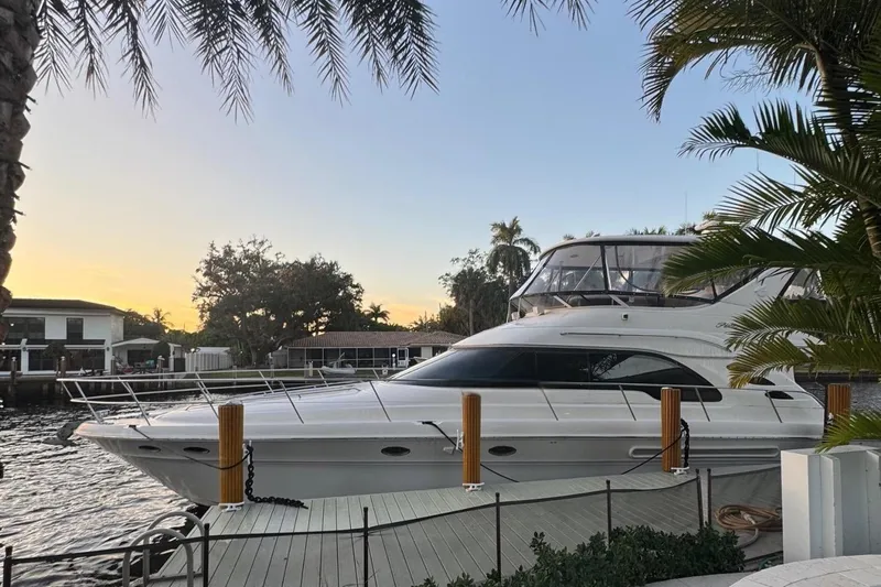 Captain Yacht Photos Pics 1999 Sea Ray 560 Sedan Bridge yacht docked at sunset, surrounded by palm trees.