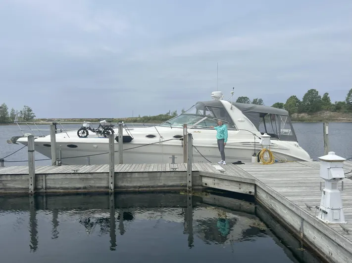  Yacht Photos Pics 1997 Sea Ray 400 Sundancer yacht docked at a wooden pier with a person standing nearby.