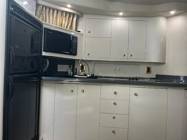  Yacht Photos Pics Interior of 1997 Sea Ray 400 Sundancer yacht kitchen with white cabinets and appliances.