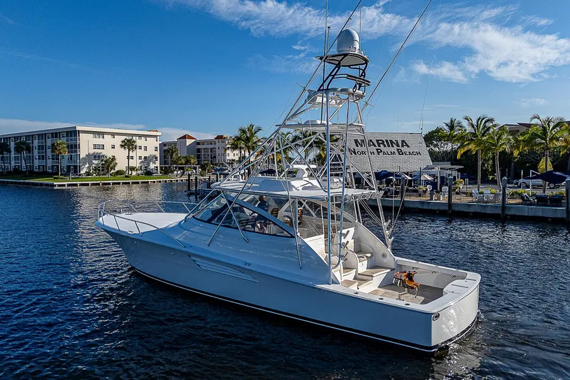  Yacht Photos Pics 2023 Viking 54 Open yacht docked in a marina, surrounded by calm waters and palm trees.