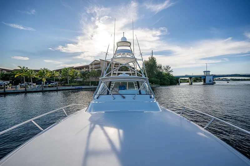  Yacht Photos Pics 2023 Viking 54 Open yacht on serene waterway under blue sky.