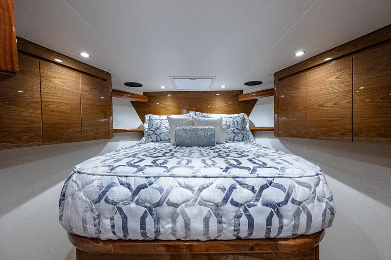  Yacht Photos Pics Luxurious bedroom interior of 2023 Viking 54 Open yacht with elegant wood cabinetry.