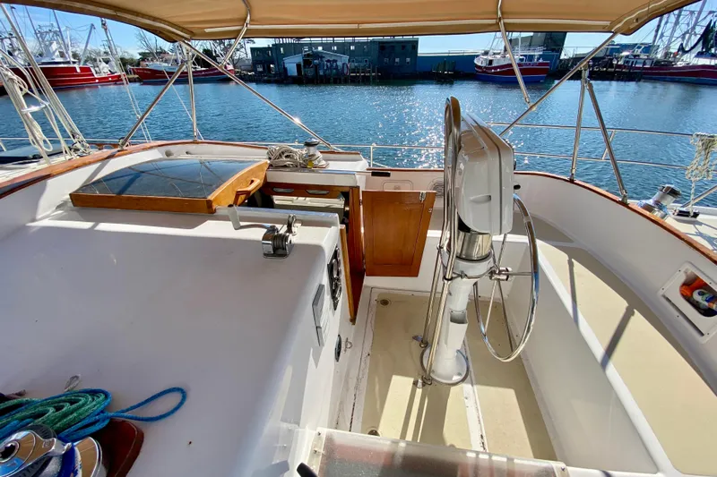 Wonder Yacht Photos Pics Cockpit of 1980 Wellington 44 sailboat with steering wheel, docked by the water.