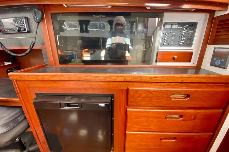 Wonder Yacht Photos Pics 1980 Wellington 44 yacht interior with wooden cabinetry, control panel, and mini fridge.