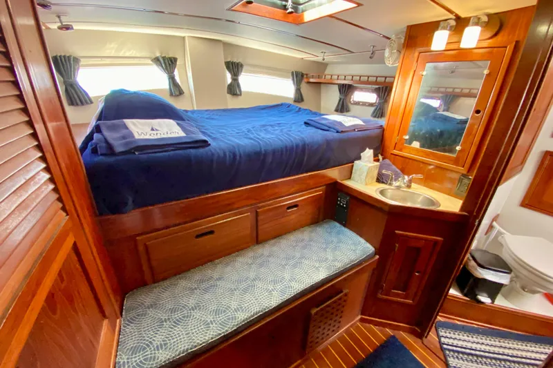 Wonder Yacht Photos Pics Luxurious cabin interior of 1980 Wellington 44 yacht with bed, sink, and wooden furnishings.