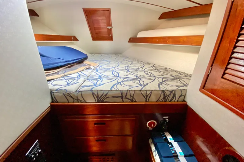 Wonder Yacht Photos Pics Cozy cabin interior of 1980 Wellington 44 sailboat with patterned bedding and wooden accents.